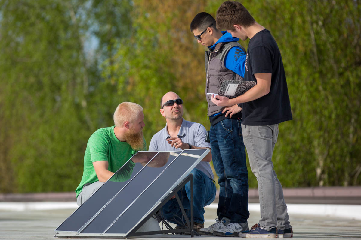 Instructor and students working outside on solar panels